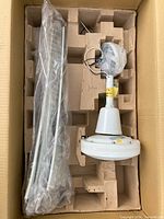 Disassembled white ceiling fan motor and parts packed in molded cardboard inside a box.