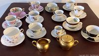 All fine china cups and saucers with gold creamer and sugar bowl displayed