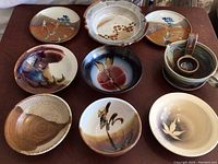Overview photo of all 9 pottery pieces arranged together on a flat surface showing color, shape and pattern variety.
