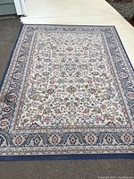 Full view of the full rectangular rug showing the floral pattern and blue decorative border.