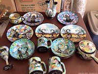 Overhead view of full set on table showing plates, bowls, mugs, goblet, covered pot and vase