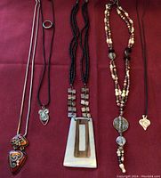 Full view of the 5 ethnic style necklaces laid out on a red cloth background.