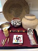 Photo showing full lot including two baskets, ceramic pot, wooden flute, beeswax candle, matchbox, and tiny pens on burgundy cloth.