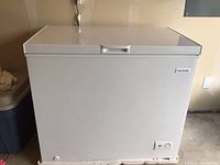Front view of white Frigidaire chest freezer showing control dial and indicator light on front bottom right.