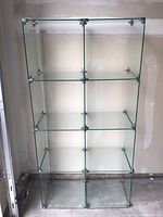Front view of assembled glass display shelf showing six compartments in a 2 x 3 grid with metal connectors at edges.