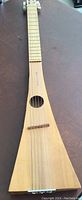 Front side view of the hand made travel guitar showing the triangular body and six strings.