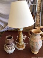 Full view of table lamp with onyx base and shade, flanked by two primitive ceramic pots.