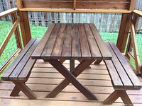 Front view of wooden picnic table with attached benches in outdoor deck setting.