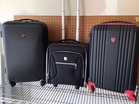 Front view showing three rolling luggage pieces: two large hard shell suitcases and one smaller soft bag in the middle.