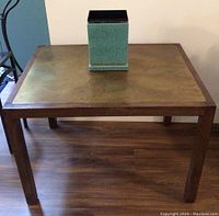 Front three-quarter view showing wooden frame and brass top