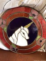 Full view of circular stained glass with unicorn and floral border for color and design reference.