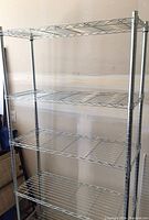 Full view of steel wire shelving rack with 4 wire shelves and tubular metal supports against wall