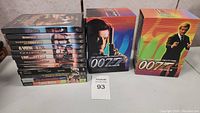 Photo showing two James Bond 007 DVD box sets and a stack of DVDs with visible spines showing multiple Bond film titles