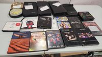 Overview photo showing CDs, DVDs, and travel cases arranged on a table, including recognizable album art for Metallica, Johnny Cash, and others.