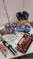 Wide shot of entire lot showing mugs, puzzles, spaceship models, lightsabers, and instruction booklet on table