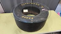 Top and angled views of the Goodyear Eagle stock car tire with a round glass top showing racing tire markings and yellow lettering.