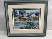 Framed oil painting showing an impressionist landscape with houses, river, and vegetation