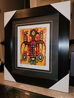 Framed art print showing full frame and mat with protective corner guards on a counter.