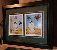 Full view of the framed Maud Lewis prints showing twoCat in teacup art pieces, side by side with green matting and black wood frame, 20x24 inches total size.