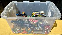 Clear plastic tote filled with LEGO pieces and instruction manuals, showing overall lot setup