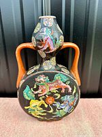 Front view of the vase showing double handles and colorful dragon design on black background.