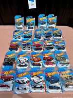 Full overview of all 24 Hot Wheels cars mint on original cards, showing packaging and cars arranged in rows and columns.
