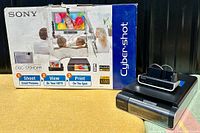 Box and photo printer unit placed side by side, box shows color promotional images and Sony branding.