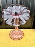 Front view of pale pink glass vase showing ruffled top flower shape and ribbed rounded base.