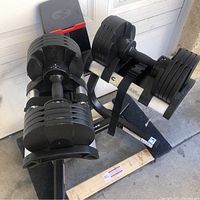 Oblique view of adjustable dumbbells mounted on stand in garage