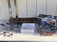 Overview photo showing the iron in box, the smart sweeper box, the two woven baskets, and the black candle wall hanger on a table outside.