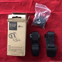 Photo showing the open packaging with two anti-tip straps and a bag of mounting hardware on a red surface