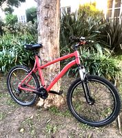 Side view of the red Decathlon CT-50 mountain bike showing the aluminum frame and overall design.