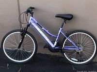 Side view of purple Girls Huffy mountain bike showing frame, wheels, seat, and handlebars.