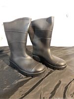 Side front view of the black rubber rain boots, showing treaded sole and overall condition.