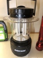 Black Rayovac lantern with clear cylindrical body and handle, shown on surface