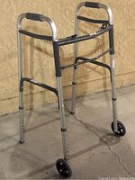 Walker with two front wheels and adjustable height, shown from one angle against a yellow wall.