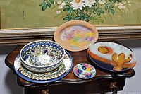 Five serving pieces displayed on a dark wooden table, showing variety in design and material including ceramic and glass items.