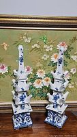 Both vases shown side by side in front of floral painting