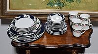 Set of floral patterned china pieces including plates, bowls, cups, and saucers on a wooden table.