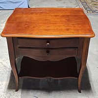 Front view of French style entry table showing polished wood top, two drawers, curved legs, and lower shelf.
