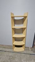 Full view of the light wood wavy bookcase with four shelves against wall