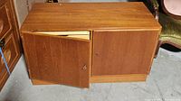 Front view of the teak credenza with doors closed partially, showing wood finish and door condition.