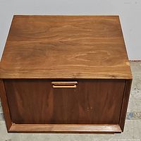 Top view of nightstand showing wood grain and small chip on front right corner.