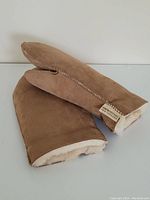 Front side of sheepskin mittens showing wool lining inside and tag attached.