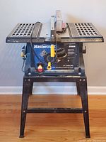 Front view of Mastercraft 10 inch table saw showing blade, work surfaces, and metal stand with adjustment knobs and safety switch