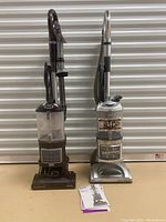 Two Shark upright vacuums side by side with accessories and manuals in front.