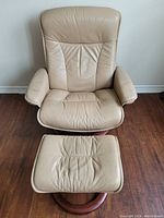 Front view of beige Stressless leather recliner chair with matching ottoman on wooden bases