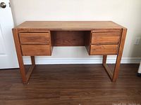Full front view of teak desk showing top, drawers, and frame