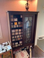 Front angle showing wood cabinet with glass sliding door and decorative frames