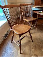 Two side chairs displayed near window showing contoured seats and spindle backs.